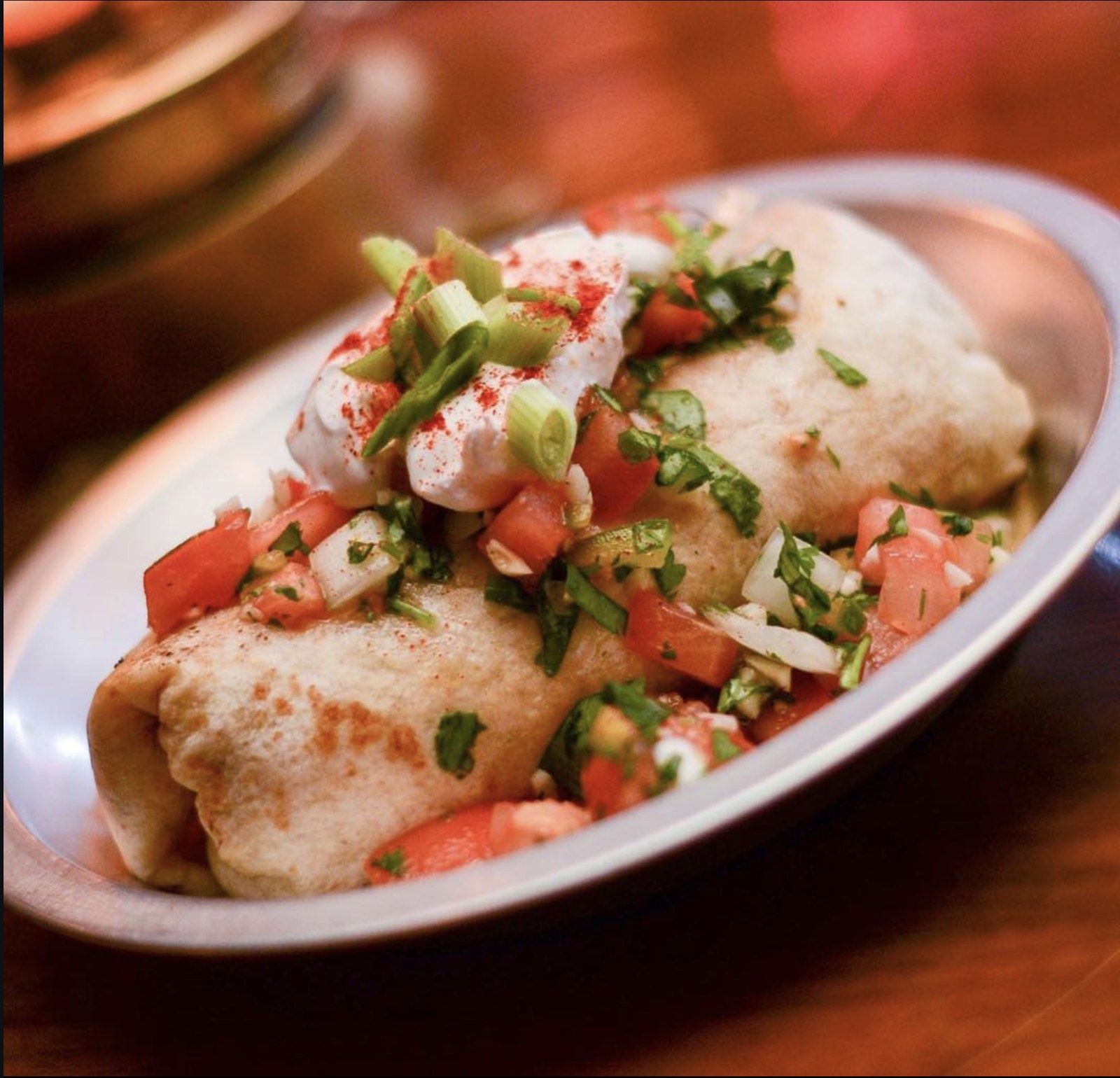 Breakfast Burrito topped with pico de gallo, sour cream, scallions and paprika
