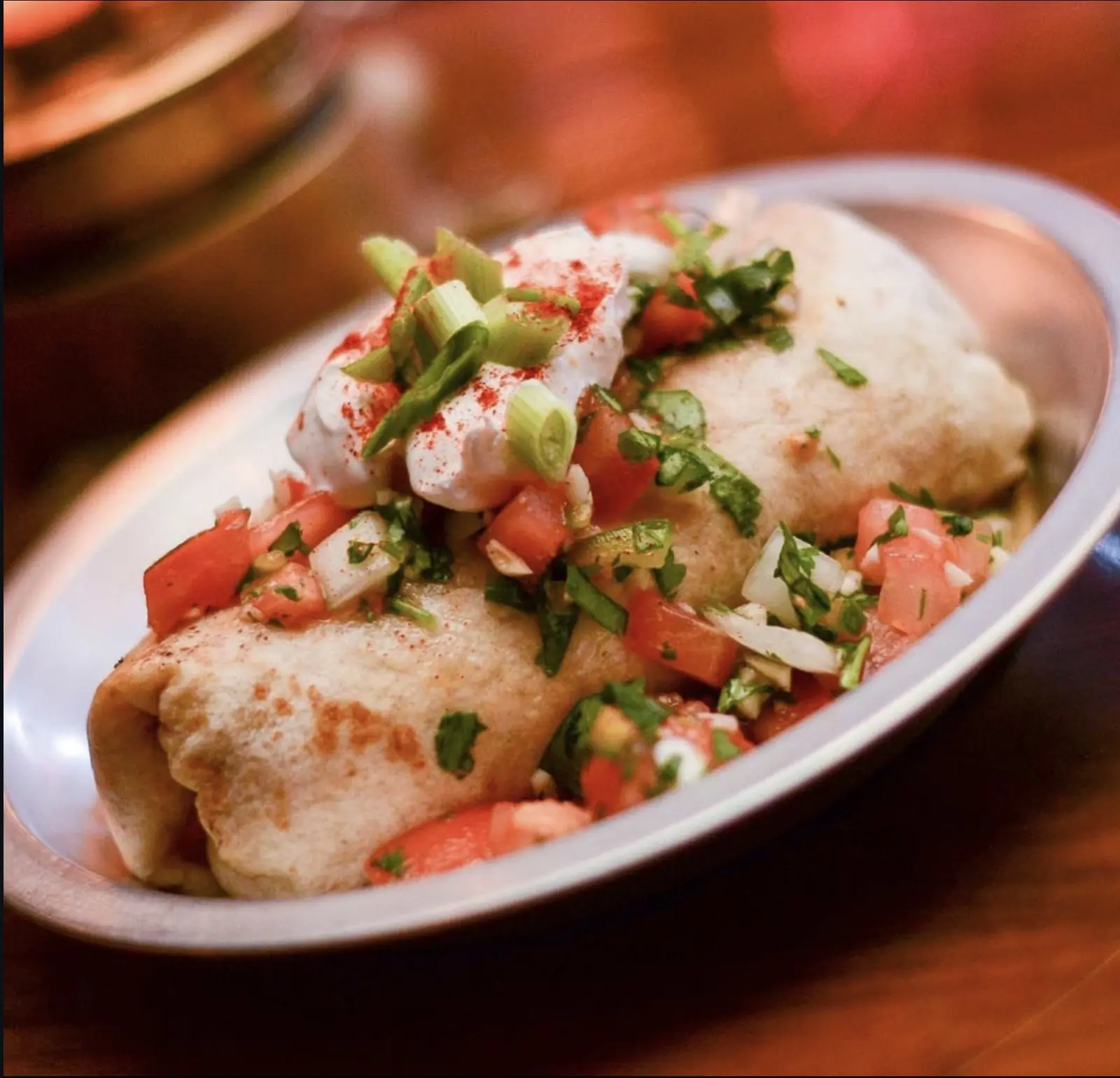 Breakfast Burrito topped with pico de gallo, sour cream, scallions and paprika