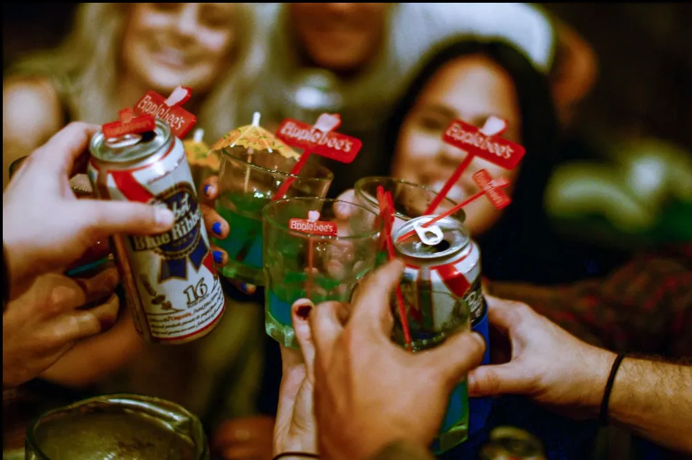 Friends toasting with PBR cans and green cocktails at Northside Yacht Club
