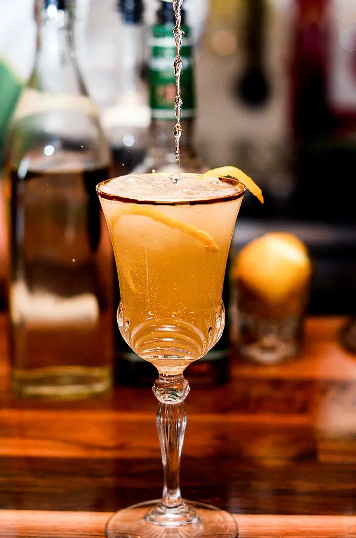 A house cocktail mid-pour in a vintage goblet