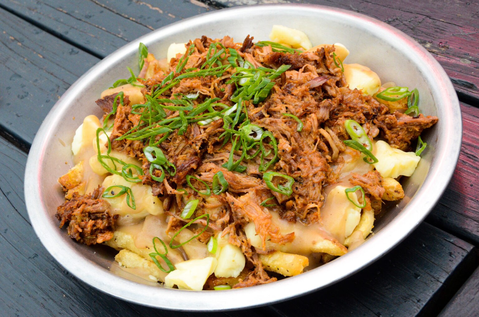 Poutine with pulled pork, brown gravy, Urban Stead cheese curds, and scallions