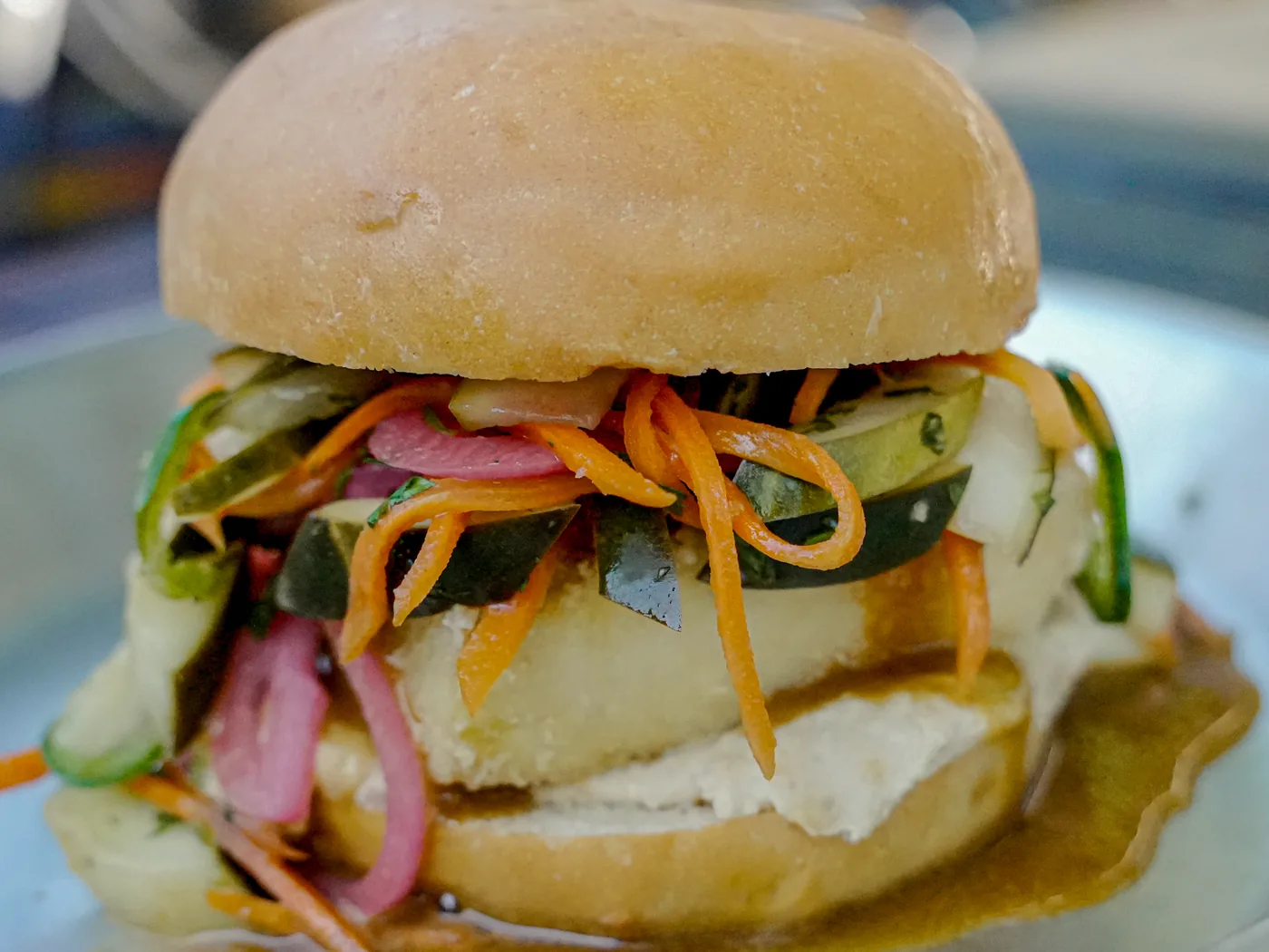 Tofu Bun Mi — lightly-fried sesame ginger tofu, roasted red pepper pâté, jalapeños and pickled carrot, cucumber and red onion on a bun